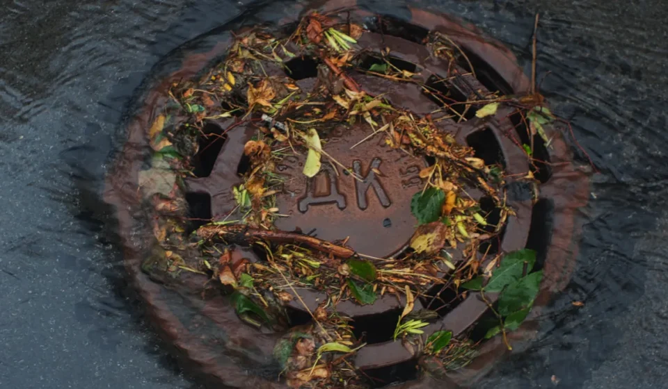 flooded storm drain cover with debris